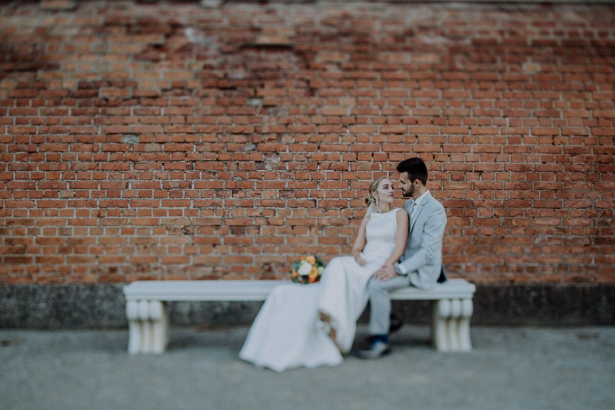 Brautpaar sitzt auf Steinbank in Schloss Hof und schaut sich verliebt an beim After-Wedding-Shooting in Niederösterreich