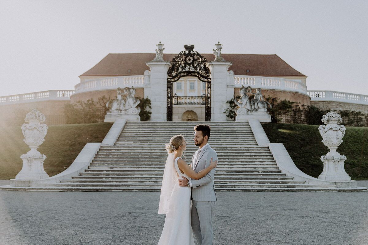 Brautpaar steht vor Schloss Hof und umarmt sich beim Sonnenuntergang After-Wedding-Shooting