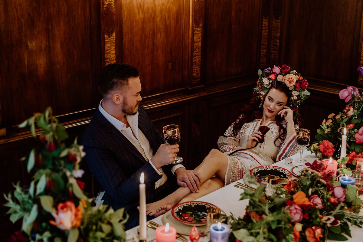 Hochzeitsinspiration Brautpaar sitzt am Brauttisch mit vielen Kerzen, viel bunter Dekoration und bohemian Flair und ganz viel Blumenschmuck boho Tischdekoration