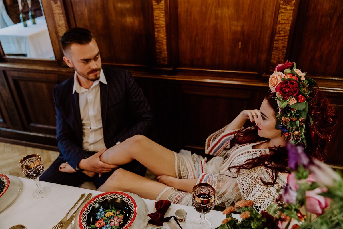 Hochzeitsinspiration Brautpaar sitzt am Brauttisch mit vielen Kerzen, viel bunter Dekoration und bohemian Flair und ganz viel Blumenschmuck boho Tischdekoration